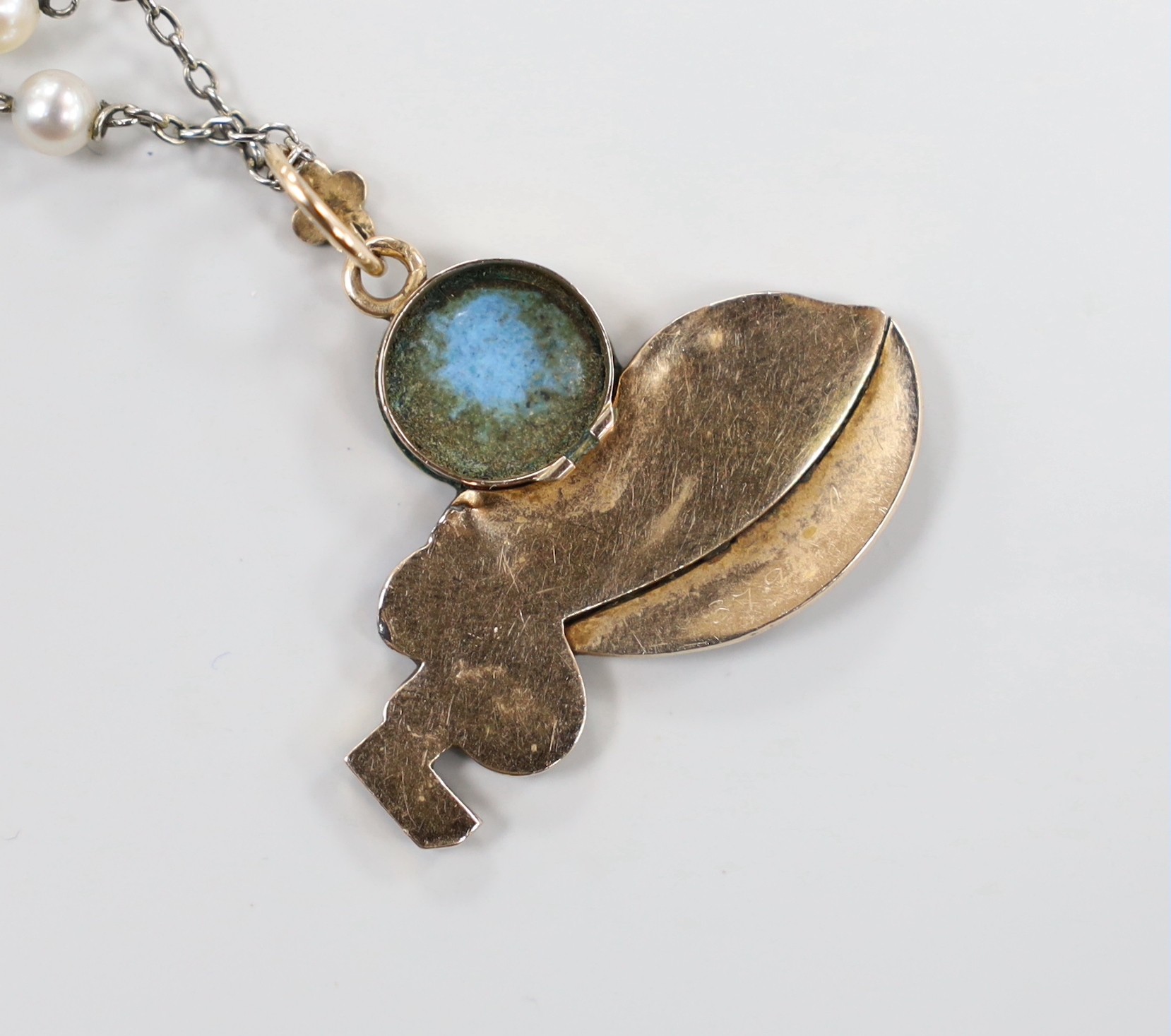 A continental yellow metal and enamel pendant, depicting a child with mandolin, 34mm, on a white metal and seed pearl chain, 38cm.